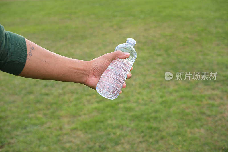 一个拉丁裔男子的特写镜头，他拿着一个标准的透明塑料瓶，里面装着水