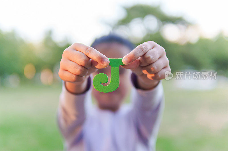 小孩拿着字母“J”