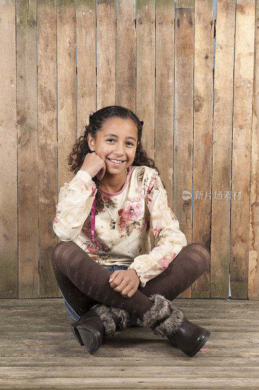 年轻女孩坐在老旧的风化的地板上