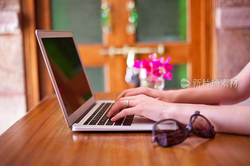 一个在热带度假的女人在酒店用笔记本电脑