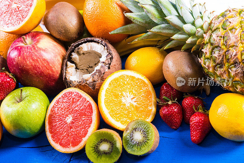 选择热带和柑橘类水果在蓝色木制盘子