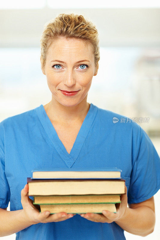 快乐漂亮的护士拿着一堆书