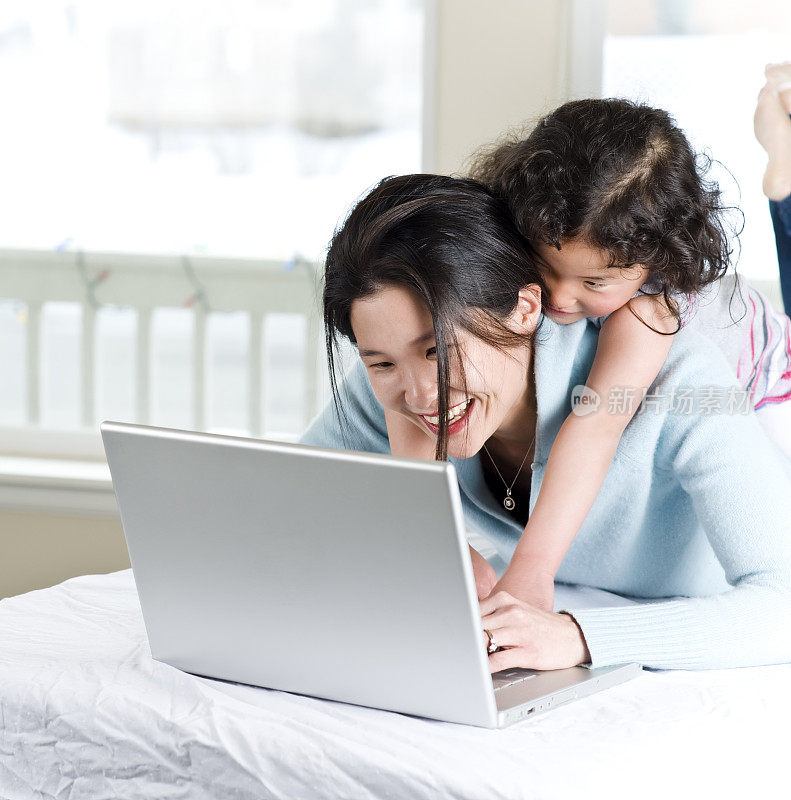 亚裔美国妈妈和女儿使用笔记本电脑