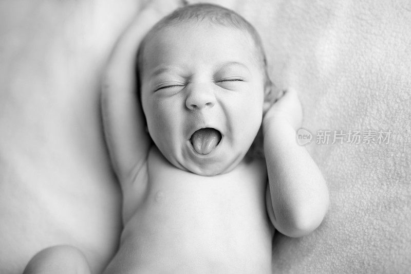 新生儿在伸懒腰时打哈欠的黑白图像