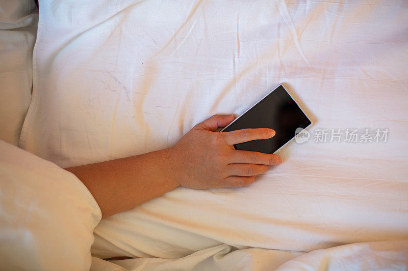 在床上睡觉时手拿着智能手机