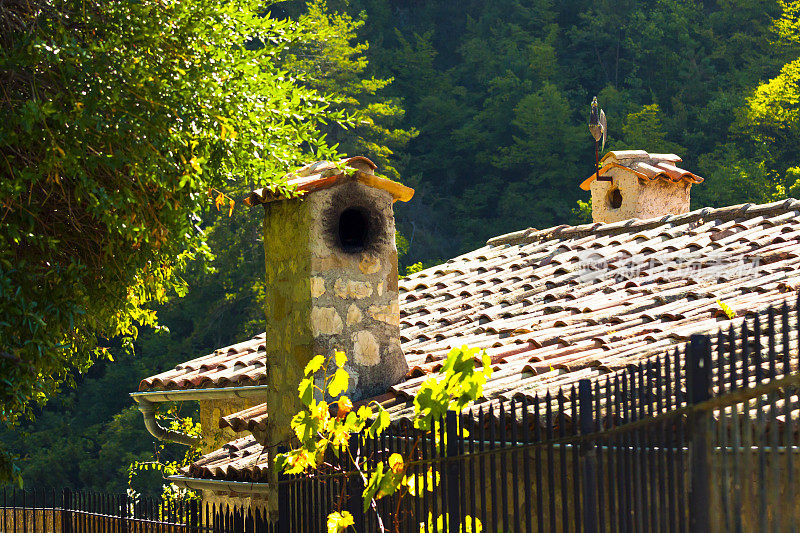 夏日阳光下的旧屋顶、烟囱和尖桩篱笆
