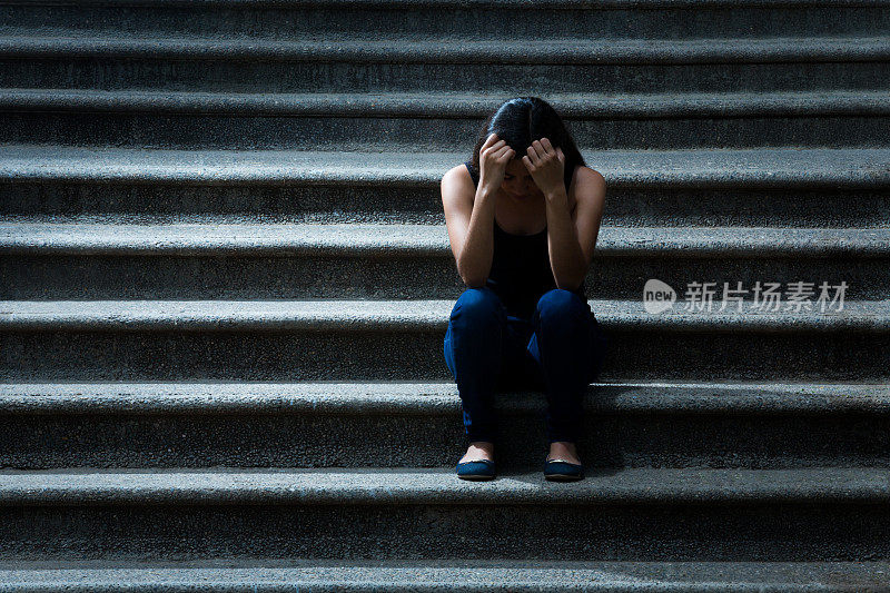 年轻女子沮丧地站在楼梯上