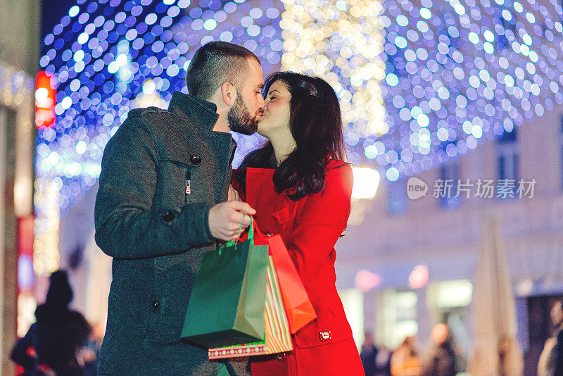 情侣在市中心购买圣诞礼物和接吻