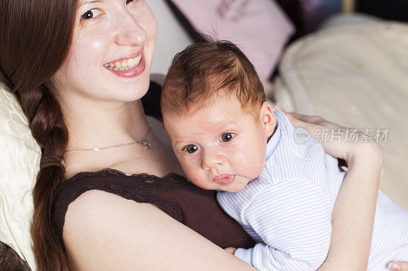 年轻的母亲和小婴儿依偎在她的胸前