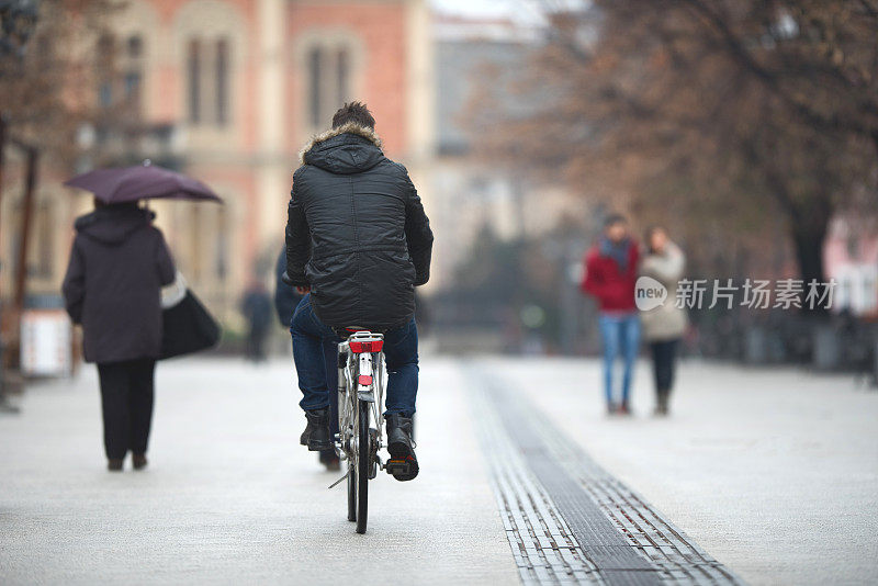 一个男人在户外骑自行车的后视图。