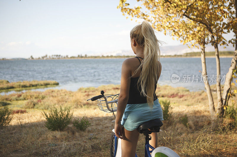 在森林里骑自行车的年轻金发女人