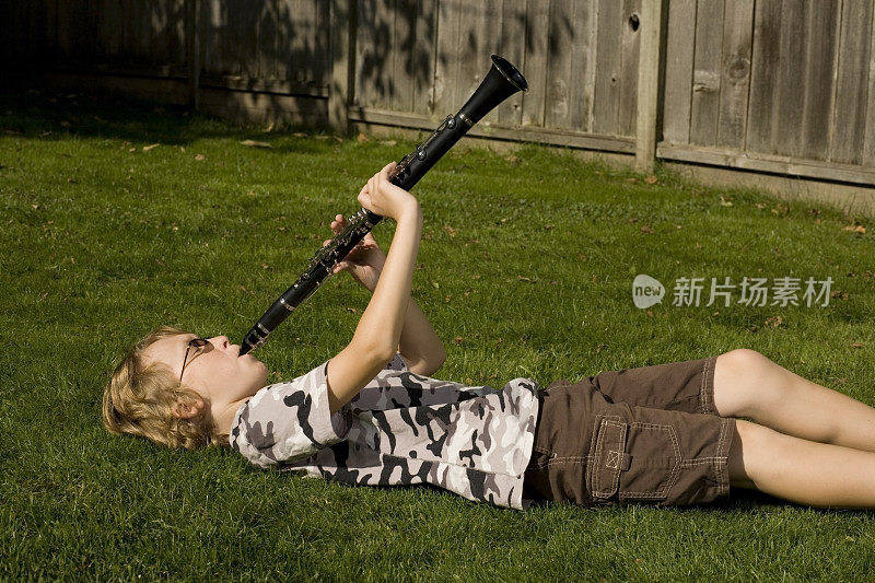 一个男孩在草地上吹他的单簧管。