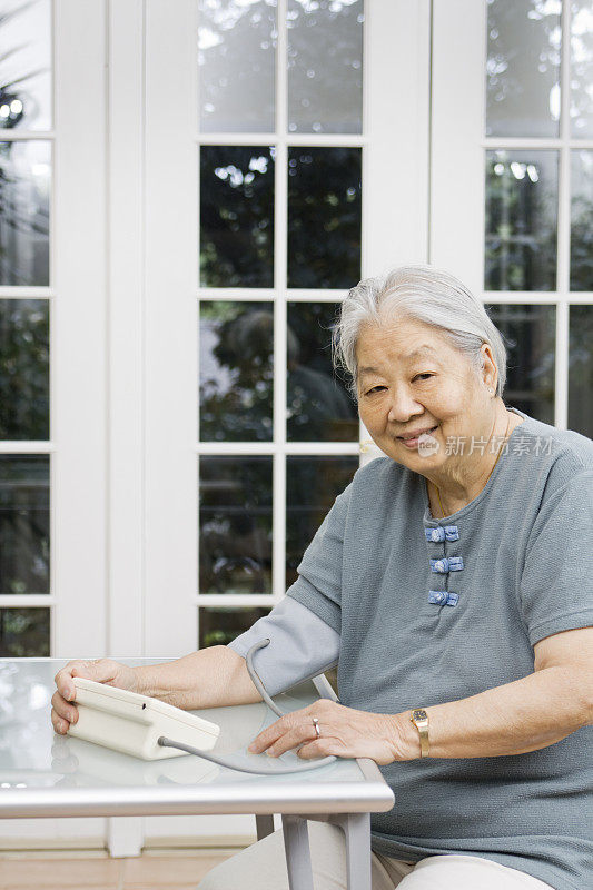 年长亚洲妇女使用血压计