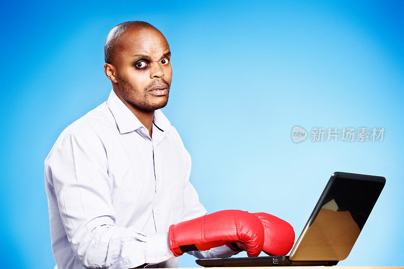 一个黑眼圈，拳击手套，笔记本电脑的不开心男人