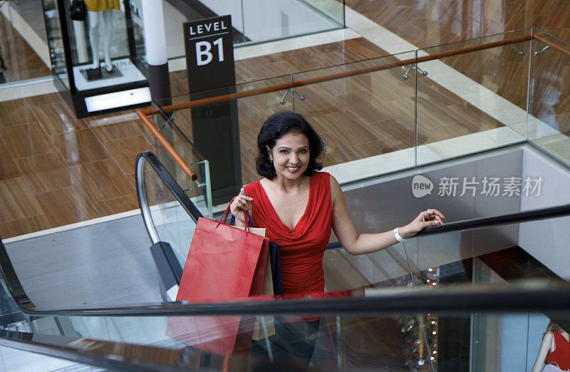 一个印度女人拿着购物袋，坐电梯