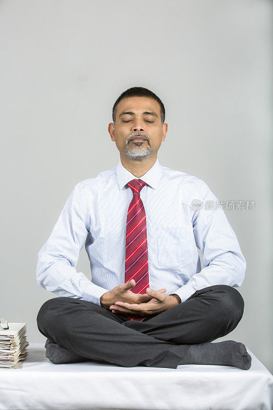 成熟的印度商人在办公室练瑜伽