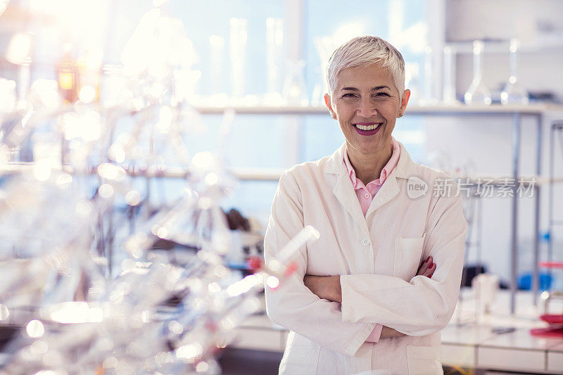 在实验室里双臂交叉的快乐女科学家。