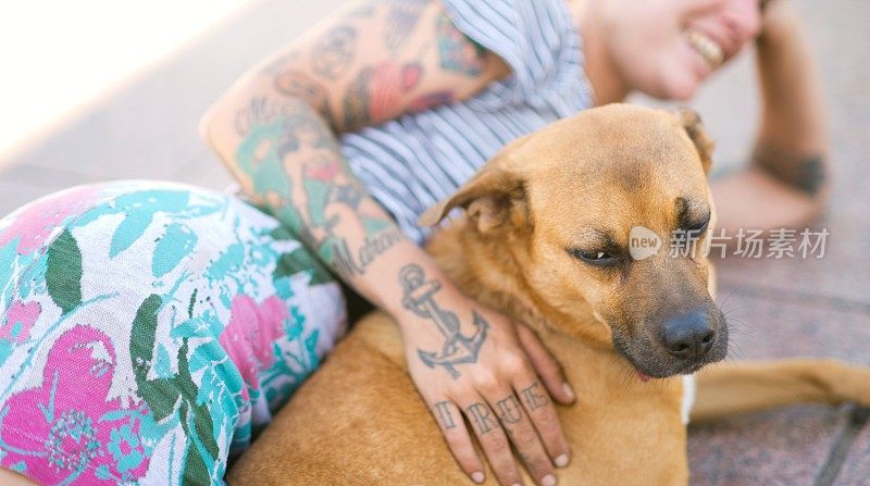 一个纹身的女人放松与狗的特写