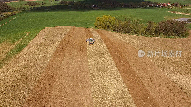 鸟瞰图美丽的农业领域在春天与拖拉机在工作-耕地