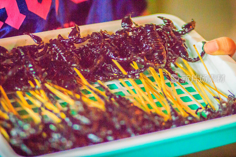 泰国曼谷夜市街头的一个小贩正在卖烤蝎子。