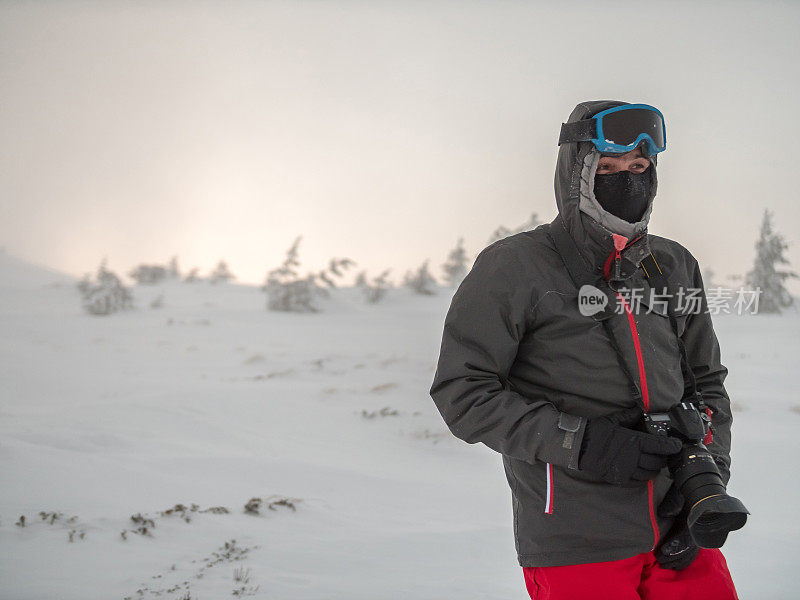 专业摄影师拿着相机，在雪山的户外检查位置