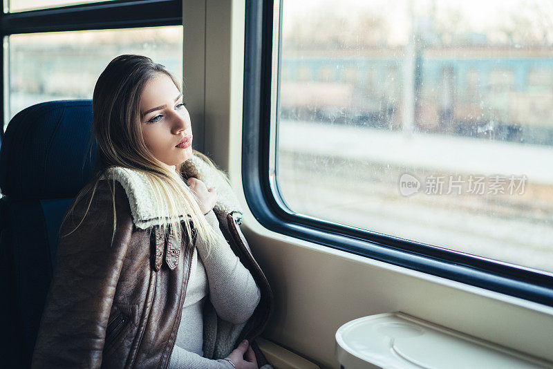 女人乘火车旅行，坐在靠窗的地方享受。