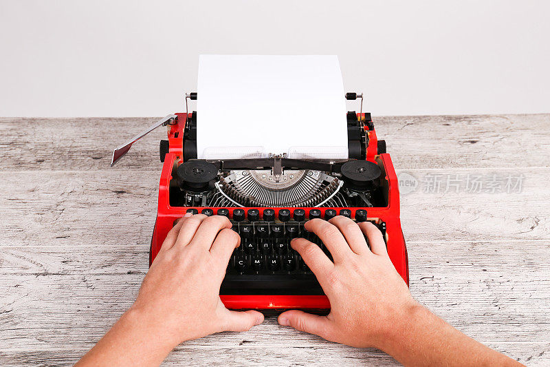 红色和黑色的复古打字机与白色空白纸在木制桌子桌上