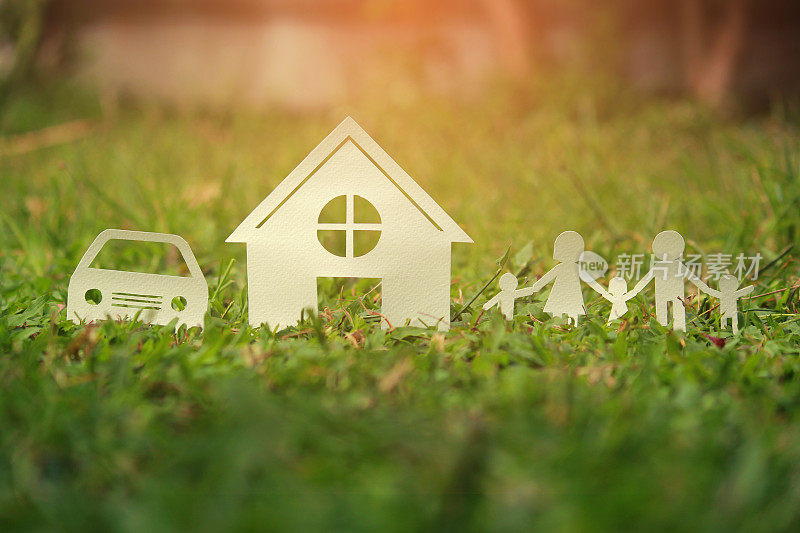 绿色草地上的家庭剪纸，为房子和汽车省钱的概念，复古色调。