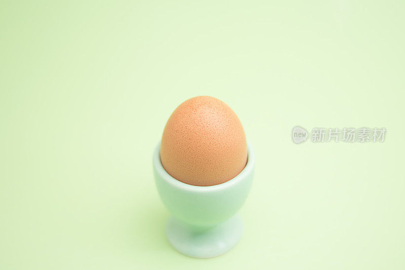 鸡蛋杯中的棕色鸡蛋，背景为绿色