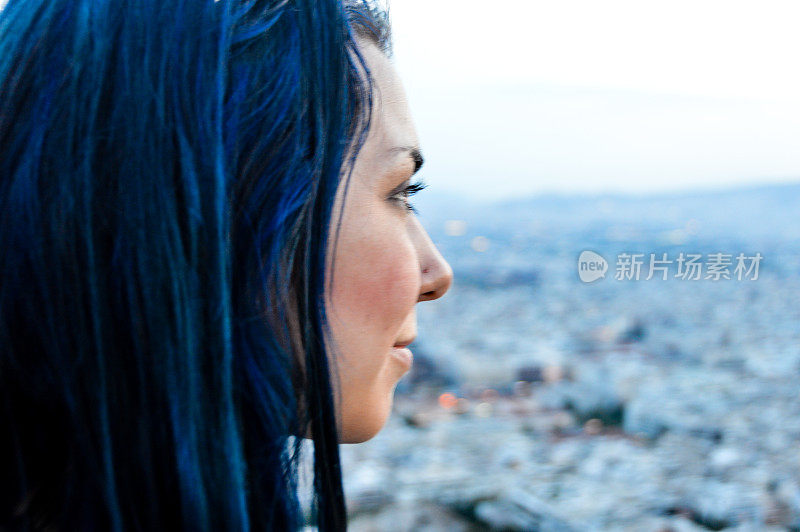年轻女子俯瞰雅典的夕阳和城市的灯火