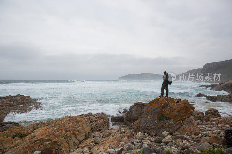 年轻男子在海岸附近徒步旅行，欣赏风景