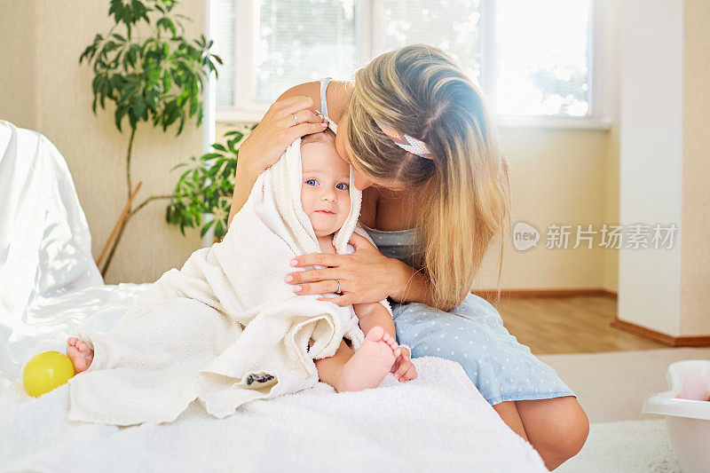 一位母亲在房间内的毛巾间拥抱她的婴儿
