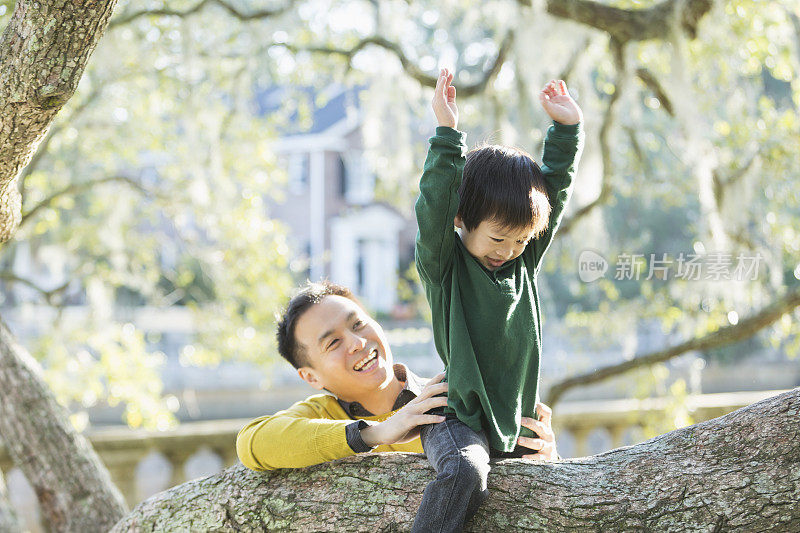 亚洲小男孩和爸爸在公园爬树