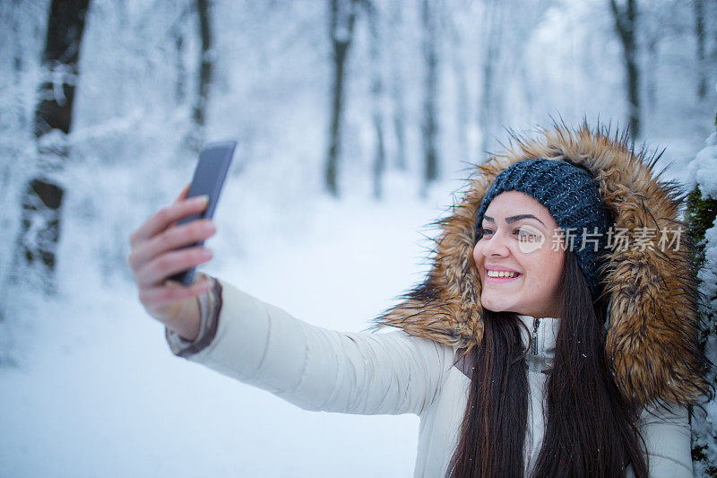 女孩享受冬天，在下雪的时候自拍