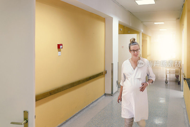 孕妇抱着肚子走在医院走廊上