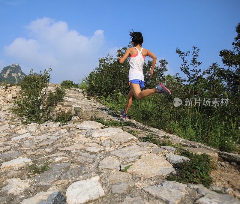 健身女子越野跑者在山顶的长城上奔跑