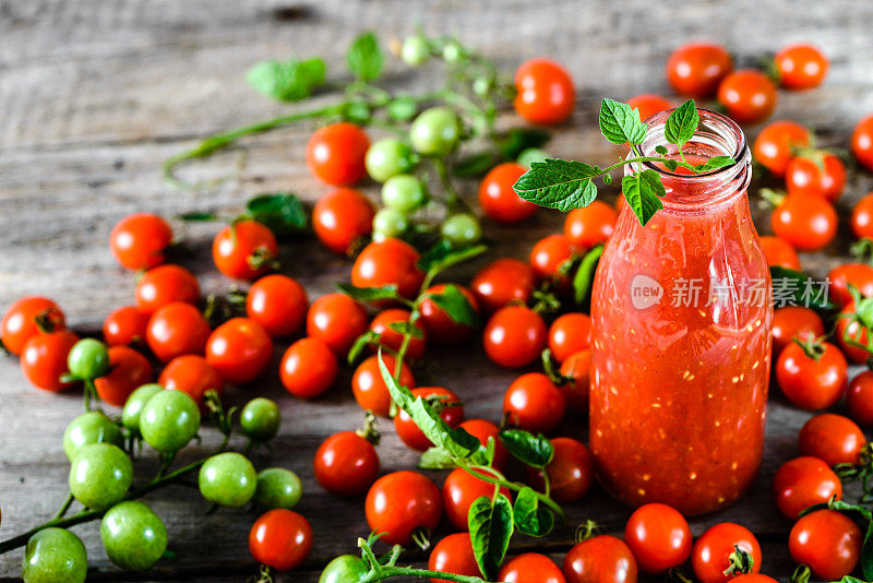 瓶番茄汁和新鲜西红柿放在木桌上，健康食品有机饮料理念