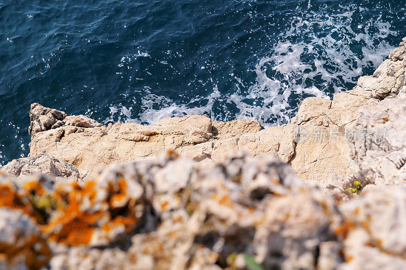 亚得里亚海海岸的岩石，地中海，特写。海浪撞击海滩岩石的鸟瞰图。石、石、红藻、海、岸、石。美丽的风景,海滨。
