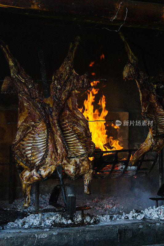 在巴塔哥尼亚，两只整羊的尸体在铁制十字架上的明火上烤着