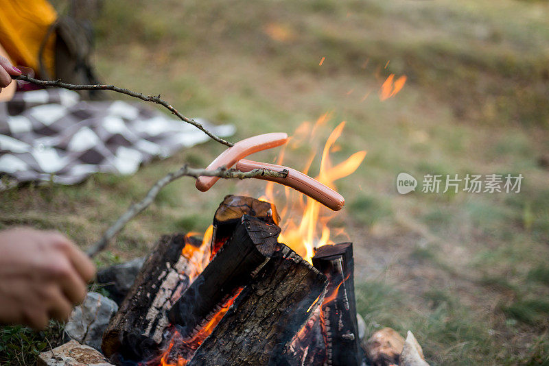 漂亮的一对，围坐在篝火旁。背景是一个帐篷，那人用一根棍子弹火。