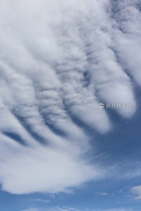 蓝色天空映衬着蓬松、缕缕白云的特写