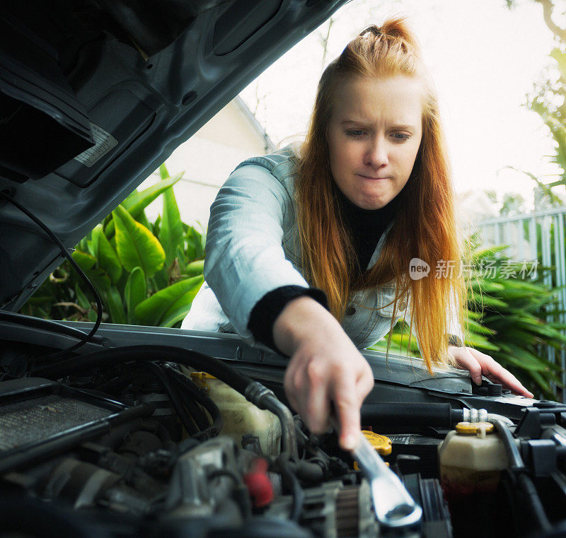 年轻女子认真地努力修理她的破车