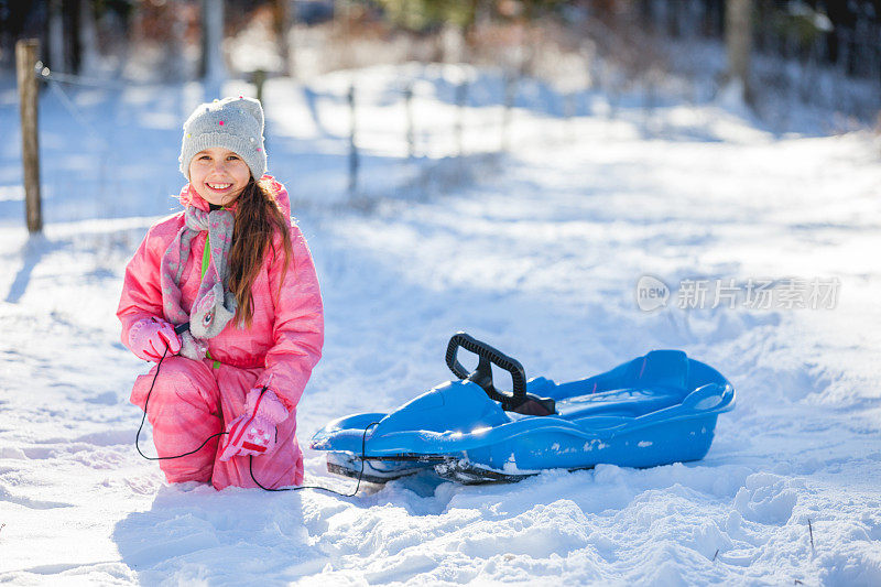 微笑的年轻女孩享受雪与她的雪橇