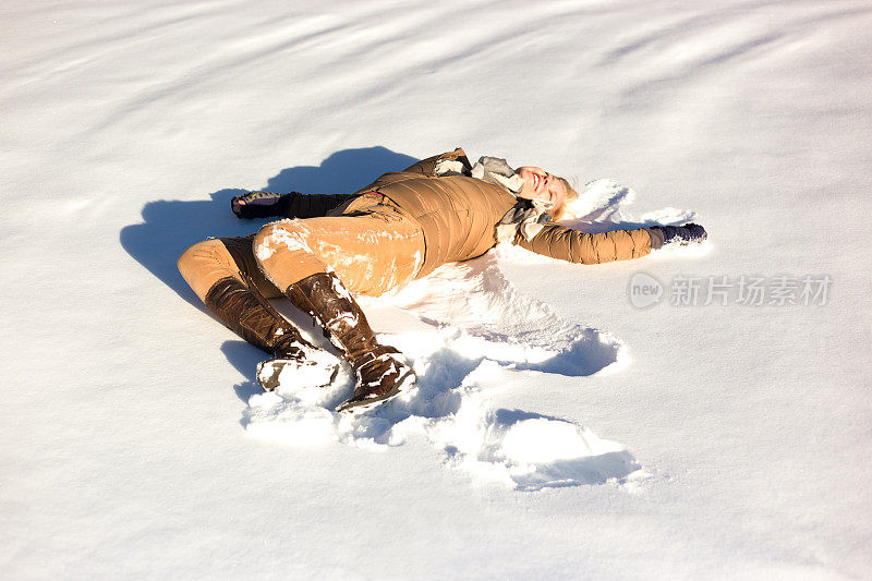 女人躺在阳光明媚的新雪