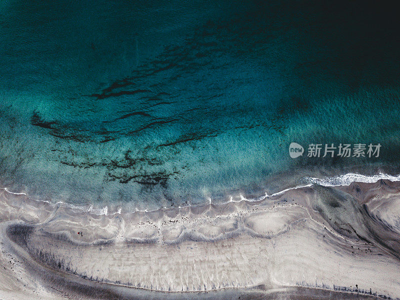 鸟瞰图夫妇呆在挪威Senja岛的绿松石色海滩