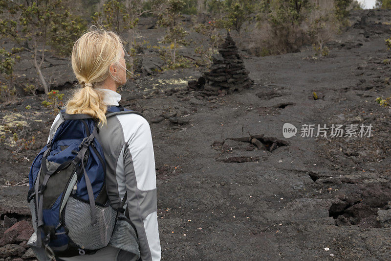 女性徒步旅行者沿着火山熔岩向前走