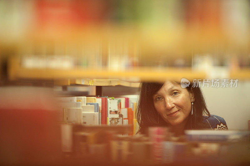 美丽微笑的女人在图书馆选书