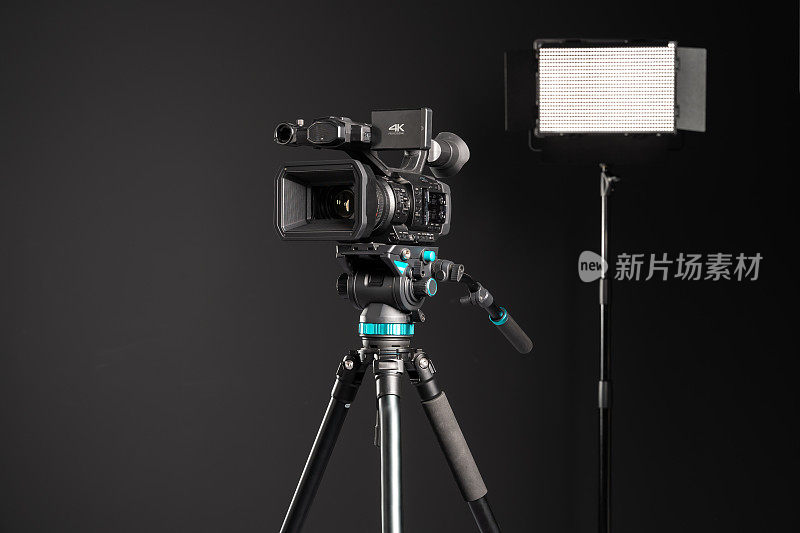 专业4K摄像机在相机三脚架和照明LED面板在黑色背景