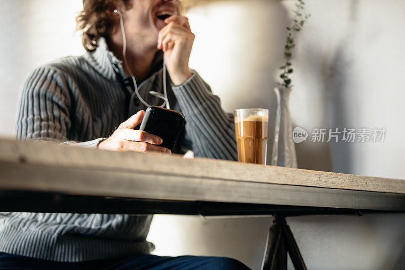 一个红头发的年轻人在咖啡店里用手机聊天