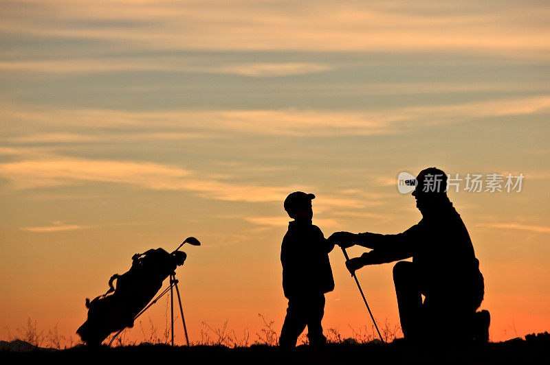 剪影年轻的高尔夫球手从他的父亲得到教训